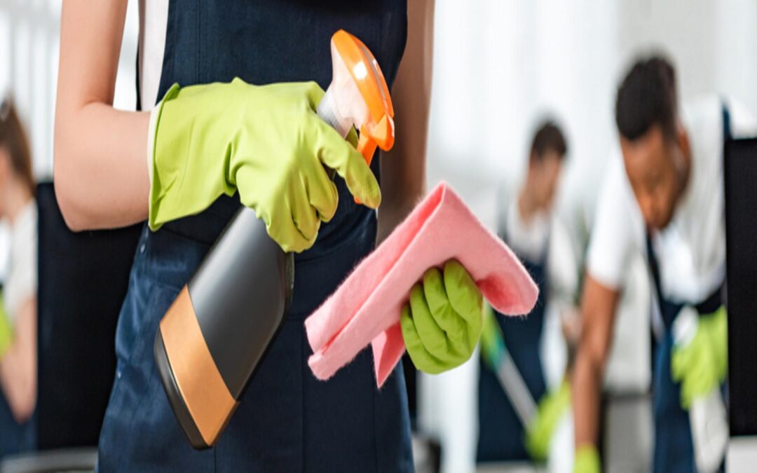 woman wearing gloves while holding a spraybottle and cleaning cloth