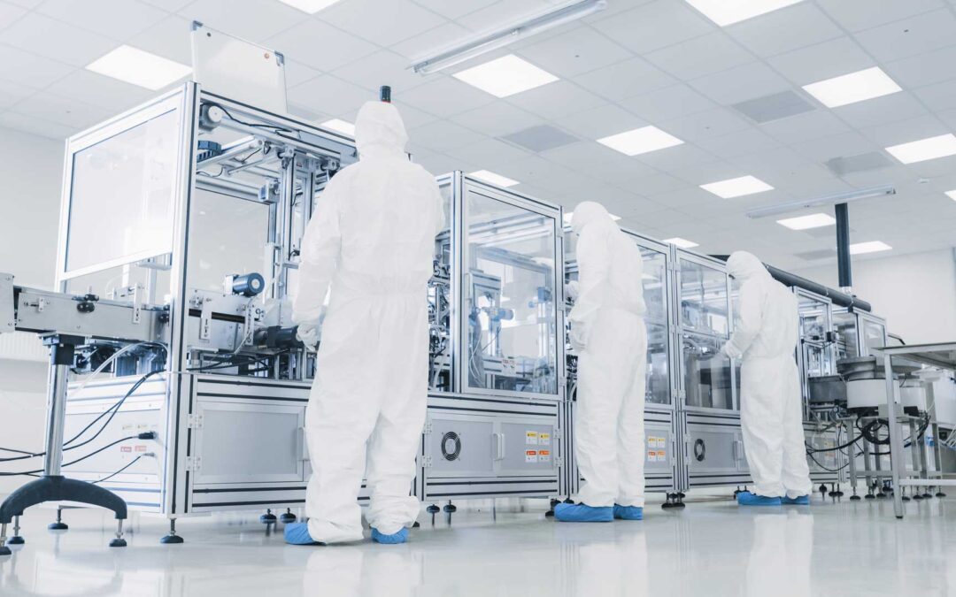 Technicians in cleanroom suits operating high-tech machinery in a sterile environment, maintaining strict cleanliness to protect sensitive equipment.